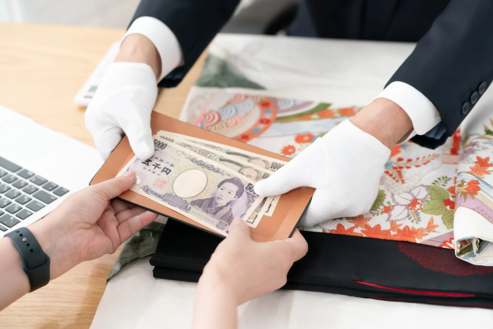 白い手袋をした鑑定士が、お客様に買取金額の現金をお渡ししている様子